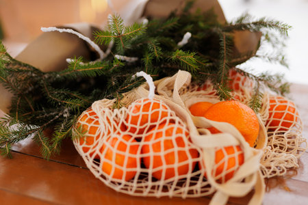 Bouquet of christmas tree banches and bag with mandarins on tableの写真素材