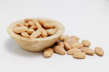 close up of wooden bowl of roasted almond nuts on white backgroundの写真素材
