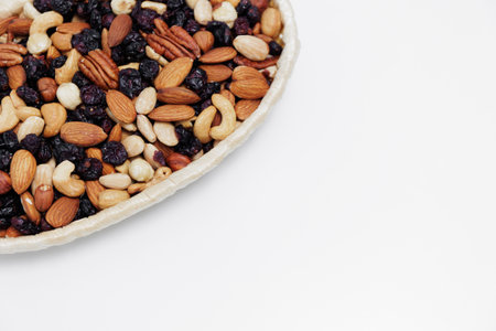 close up of various nuts in wooden bowl over white table background