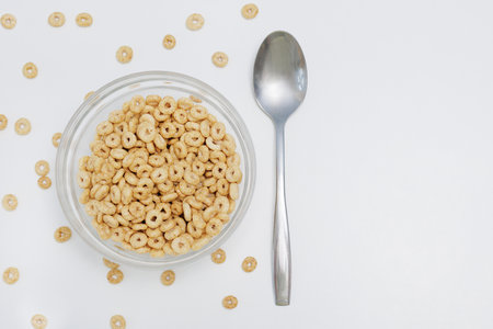 Loops cereals served in glass bowl with metal spoon on white with copy spaceの写真素材