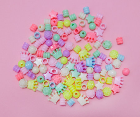 Top view of multi-colored kids beads on pink backgroundの写真素材