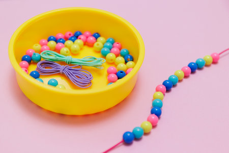 Box with multicolored beads and handmade jewellery on pink backgroundの写真素材