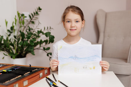 Little girl shows her painted picture in her room