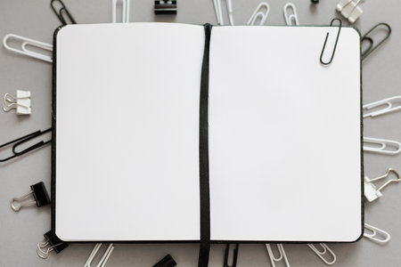 notepad with blank pages and various type of paper clips over grey backgroundの写真素材