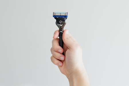 Man's hand holding razor on white backgroundの写真素材