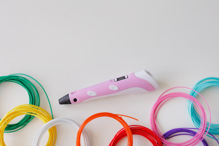 3d pen and kit of colourful plastic filament on white background with copyspace for text