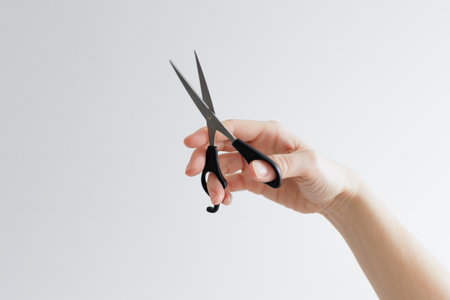 Woman's hand holding scissors on white background with cpyspaceの写真素材