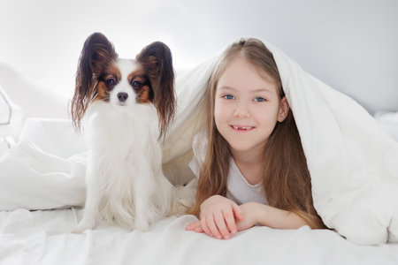 portrait of cute little girl with her cute dog on the bedの写真素材