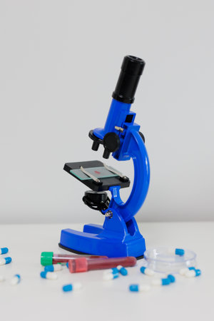 Blue metal microscope and pills on white table