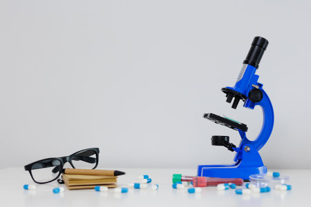 Blue microscope, eyeglasses and pills on white table