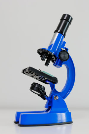 Side view of blue metal microscope on white table