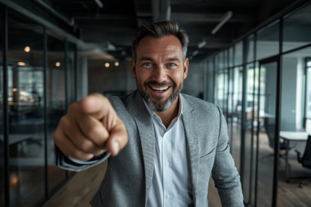 happy surprised businessman pointing at you in modern office background, career and job search conceptの素材