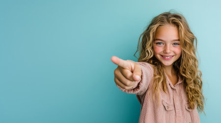 happy teenage girl pointing forward to camera over bright studio background with copy spaceの素材