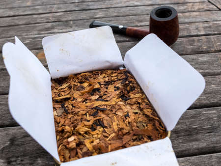 Pipe tobacco English Mixture in open box and pipe in the background on wooden tableの写真素材