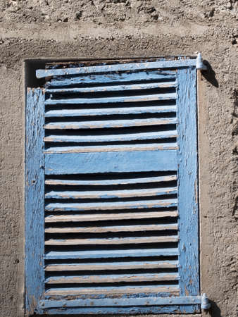 Old blue wooden window on white wall spoiled by atmospheric agentsの写真素材