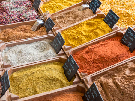 small wooden crates with various types of minced spices and grains: curcuma, curry, cajun, keufta, paprika and various infusions.の写真素材