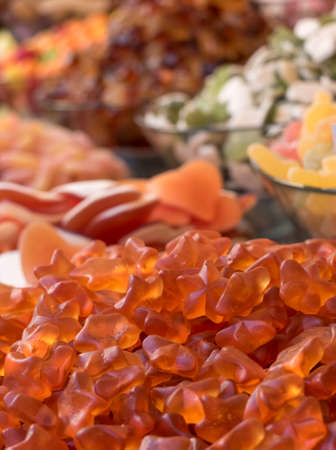 Close up of soft orange fruit candies. The candies are piled up on a stand and have different...