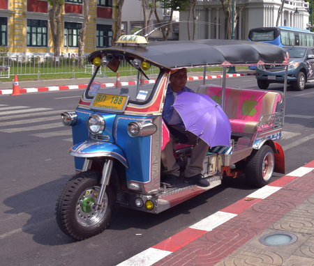 Thai Traditional Taxi known as Tuk Tuk with its driver  in Bangkok, Thailandのeditorial素材