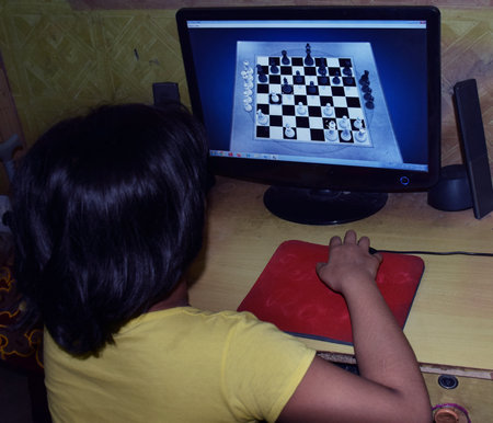 Back shot of an Indian girl playing board game Chess with computerのeditorial素材
