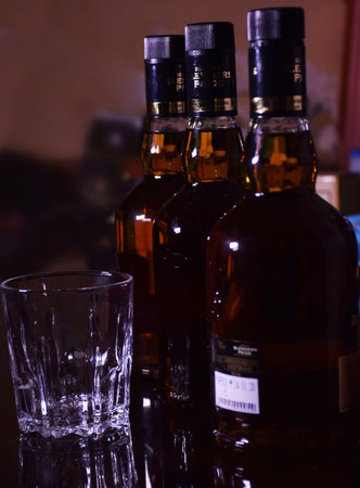 Three Bottles of  whisky with an empty glass. Whisky or whiskey is a type of distilled alcoholic beverage made from fermented grain mashのeditorial素材