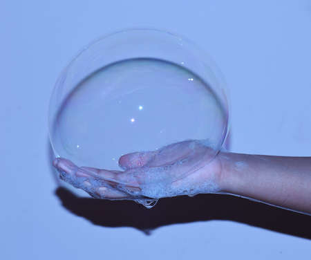 A big soap bubble in hand of a child