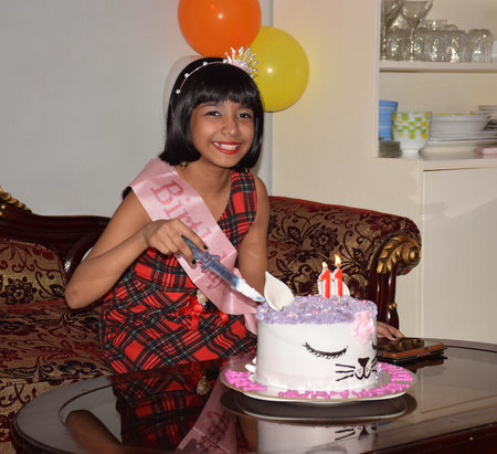 An Indian cheerful girl celebrating her birthday by cutting cakeのeditorial素材