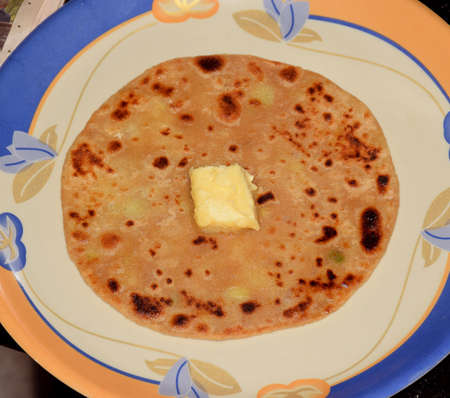 Indian popular breakfast spicy aloo paratha served with butter cube on top of itの写真素材