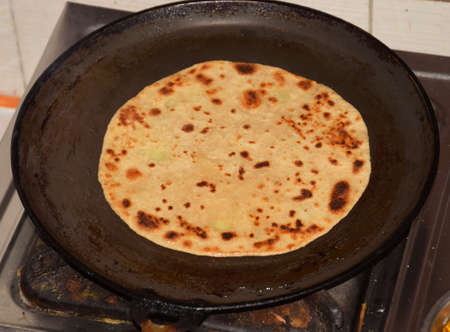 Close up of Traditional Indian Aloo Paratha preparation in progress on a round panの写真素材