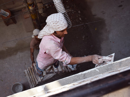 Indian construction worker smoothing side wall of a home with Plaster of Paris also known as POPのeditorial素材