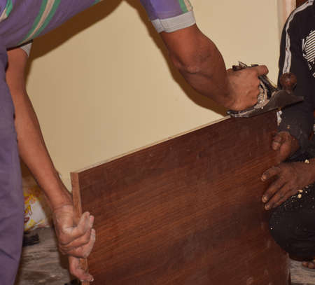 Indian carpenter using a Steel Block Carpenter Plane for smoothing a wooden surfaceの写真素材