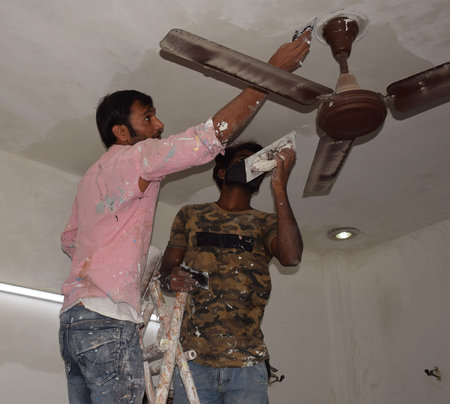 Indian painters or construction workers smoothing a wall by Plaster of Paris before painting it.のeditorial素材