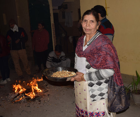 Lohri Festival - Indian Women with a bowl full of groundnuts and popcorn ready to distribute during Lohri Celebrationのeditorial素材