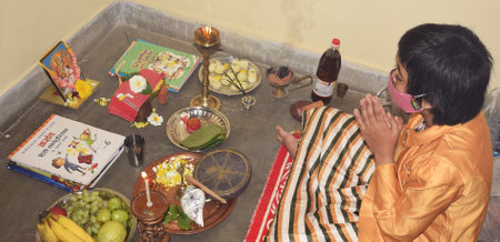 An Indian girl while wearing mask praying to goddess Saraswati during Saraswati Pooja also known as Basant Panchami in Indiaのeditorial素材