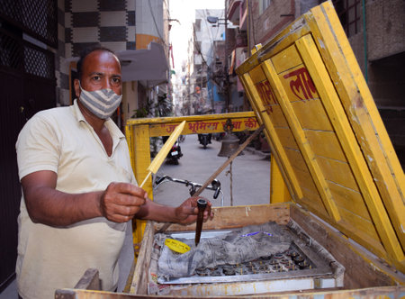 Indian Kulfi vendor giving Kulfi to a customer. Kulfi is a frozen dairy dessert originating in the Indian subcontinentのeditorial素材