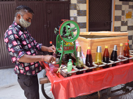 A man selling Indian famous popsicle or Chuski . Chuski is a tangy sweet syrup which is poured on the crushed ice and then enjoyed by licking itのeditorial素材