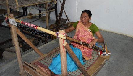 A woman weaver uses a loom to make a hand woven saree at  her workshop.のeditorial素材