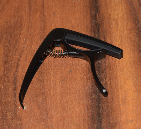 Black colored Guitar Capo attached on Guitar Fret board . Capo is a small device that clamp down on all strings across the guitar fret board to raise the pitch of the guitar.の写真素材