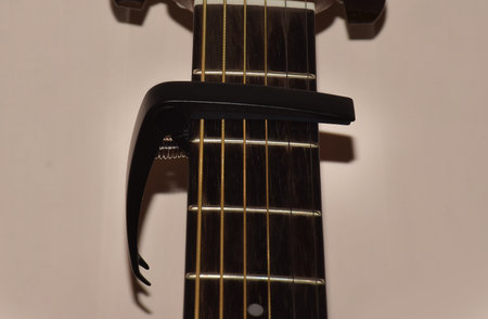 Black colored Guitar Capo attached on Guitar Fret board . Capo is a small device that clamp down on all strings across the guitar fret board to raise the pitch of the guitar.の写真素材