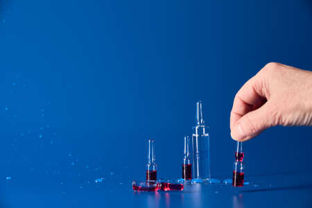 Medicines with red liquid lie on blue background