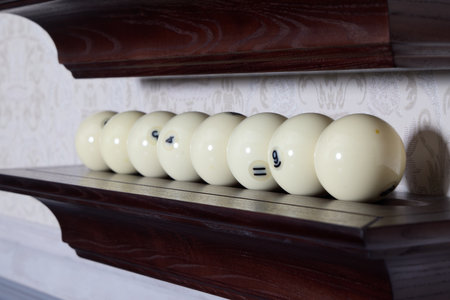A beautifully arranged collection of classic billiard balls displayed elegantly on a wooden shelf