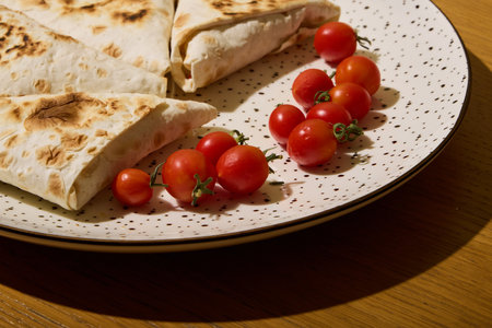 Enjoying Delicious Tortillas Piled High with Juicy Cherry Tomatoes Beautifully Displayed on a Plateの写真素材