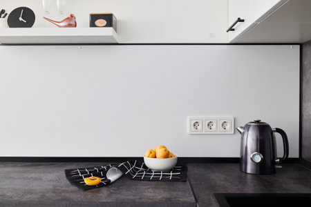 A Modern Minimalist Kitchen featuring Vibrant Citrus Fruits and a Sleek Electric Kettleの写真素材