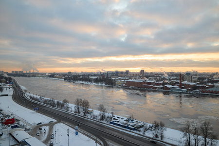 A stunning winter sunset glows over the river, framed by a serene, snowy landscapeの写真素材