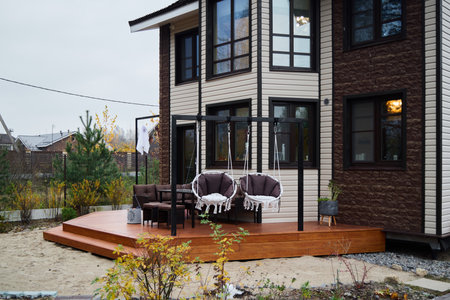 A stunning modern house exterior featuring a cozy deck with inviting swing chairs for relaxationの写真素材