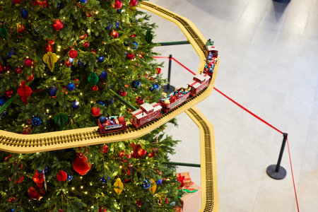 A colorful festive holiday train is circling around a beautifully decorated Christmas treeの写真素材
