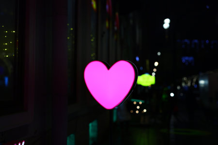 A Vibrant Neon Pink Heart Set Against a Stunning Urban Nightscape Full of Charm and Lifeの写真素材