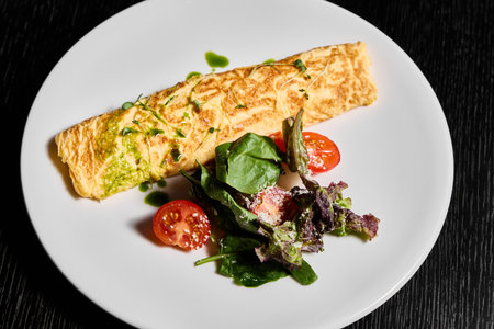 Savor a delicious omelette paired perfectly with a fresh salad and vibrant cherry tomatoesの写真素材