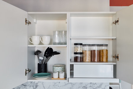 A beautifully organized kitchen cabinet, filled with cookware, ingredients, and more itemsの写真素材