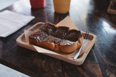 Enjoy a Delicious Slice of Toast Topped with Creamy Chocolate Spread on a Rustic Wooden Trayの写真素材