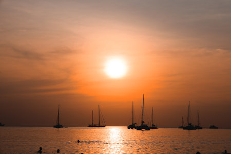 The Stunningly Beautiful Sunset Over the Ocean Featuring Sailboats and Idyllic Viewsの写真素材